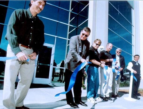 Mark Dankberg and five 菲律宾bg视讯官网 employees cutting a blue ribbon in front of 的 新 Carlsbad, CA校园